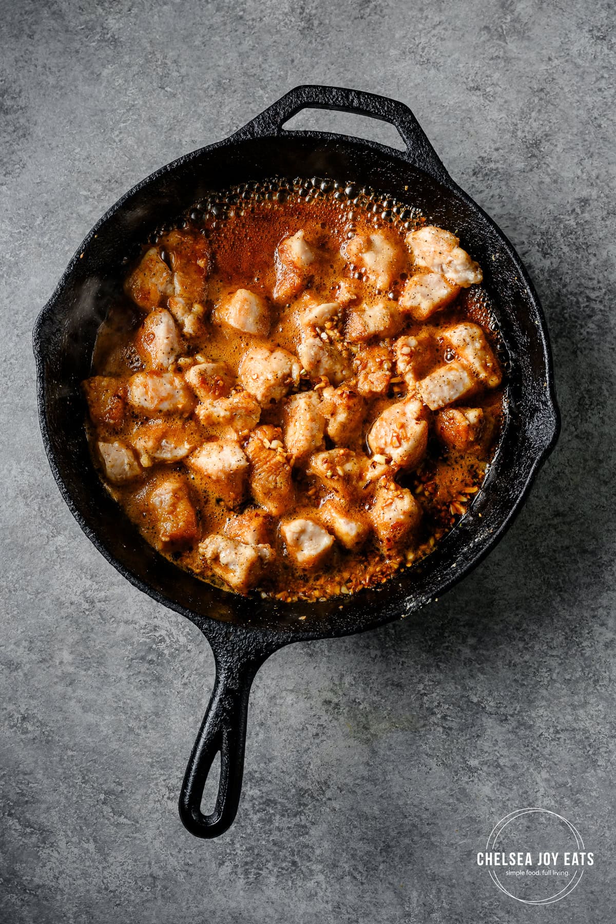 Honey garlic chicken cooking in a cast iron skillet