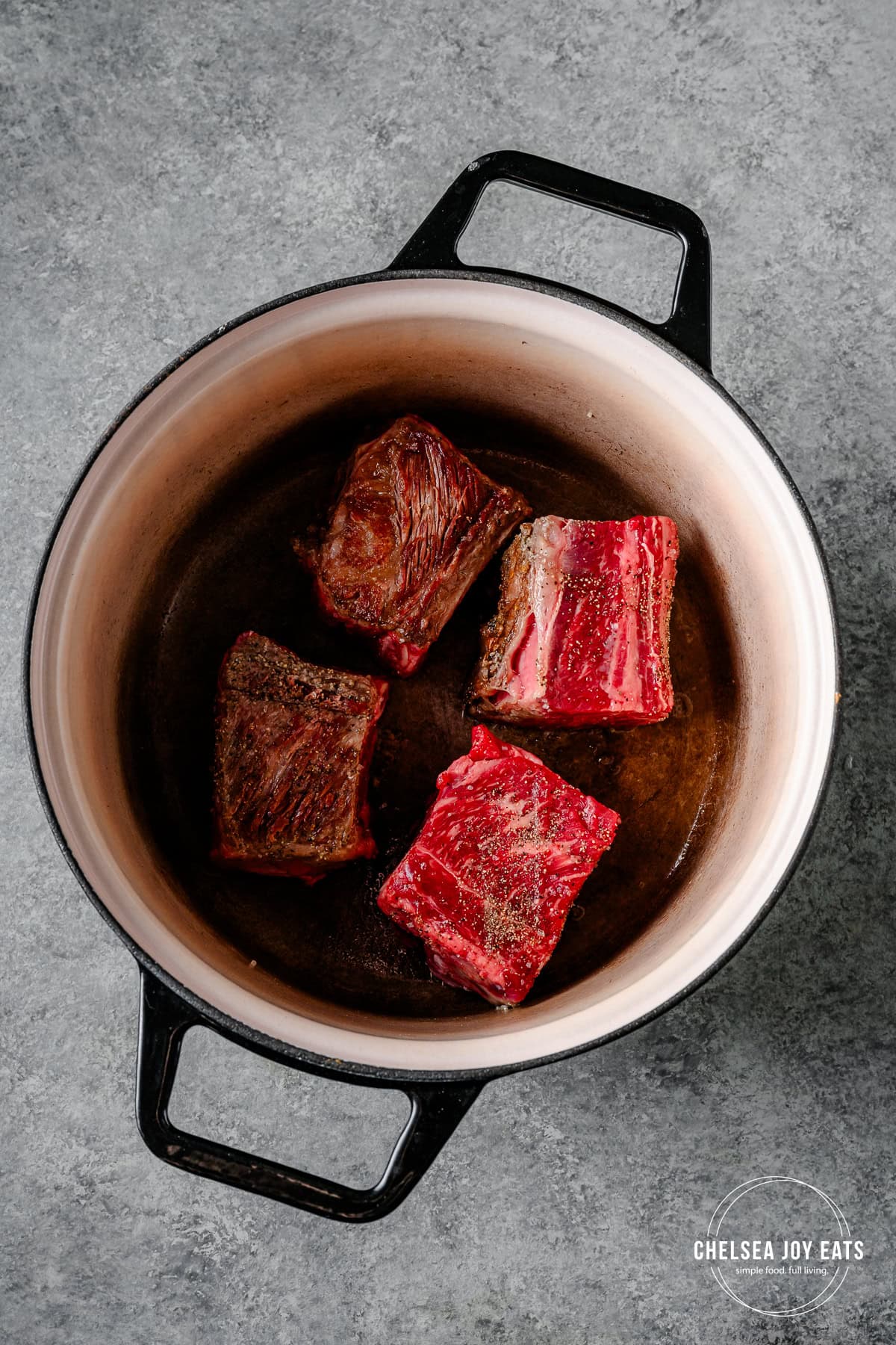Beef short ribs cooking in a Dutch oven.