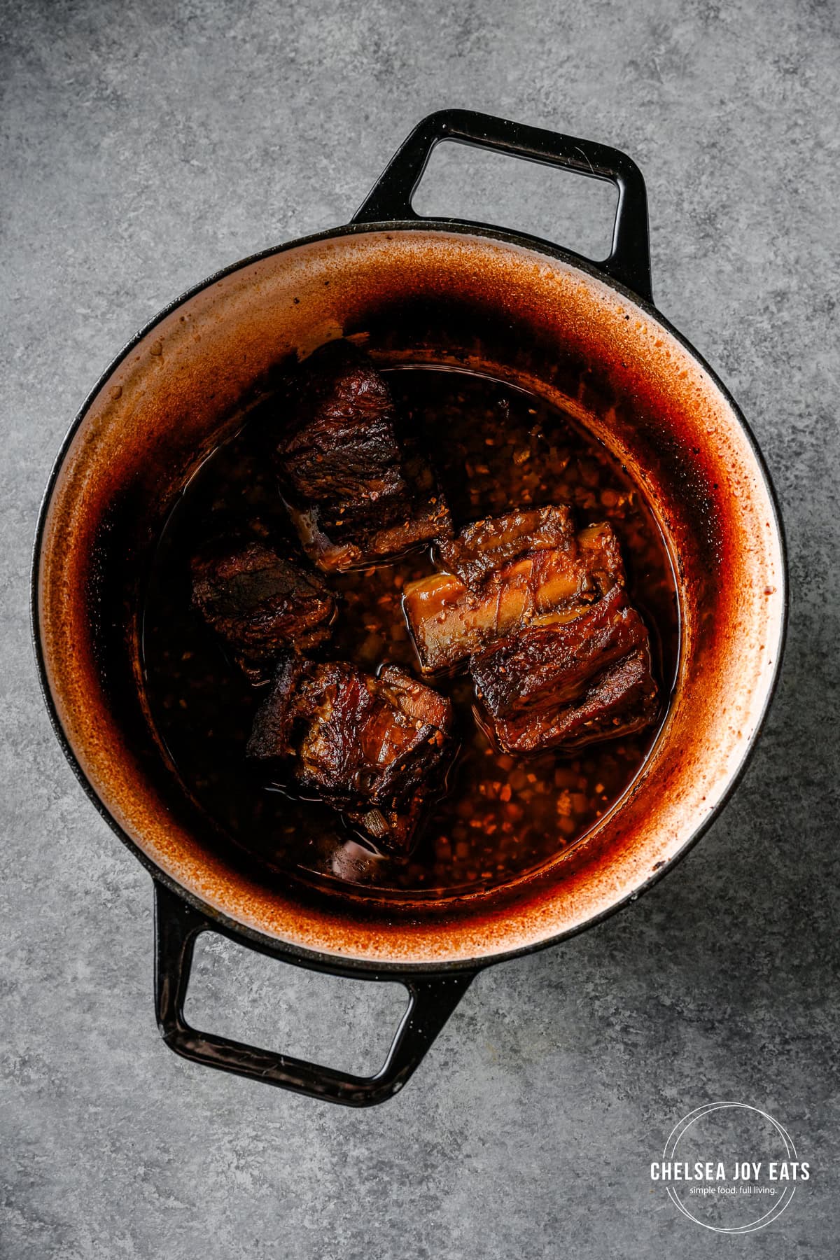 Braised beef short ribs with ginger and scallions in a Dutch oven.