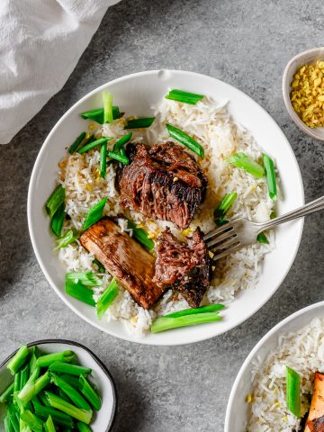 Bowl with rice and ginger scallion short ribs, garnished with ginger and scallions.