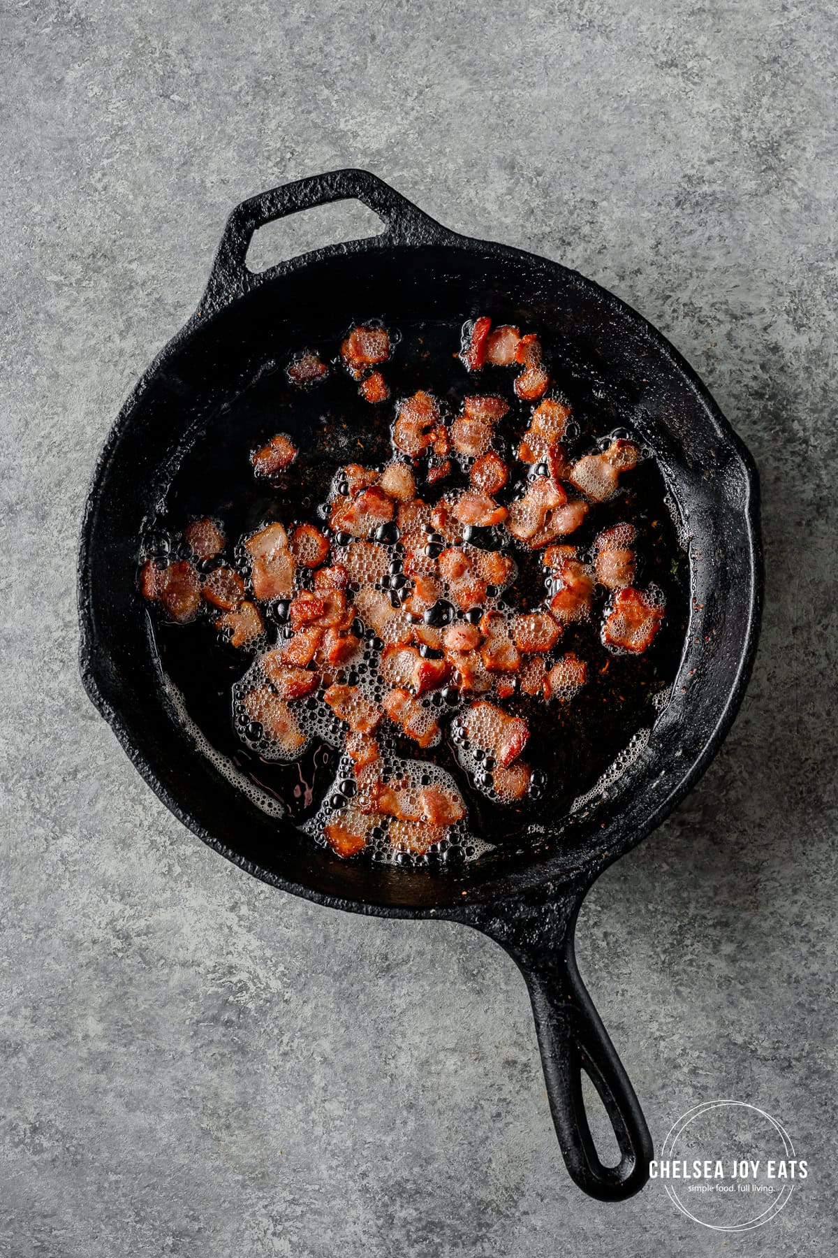 Crisped bacon pieces in a cast iron skillet.