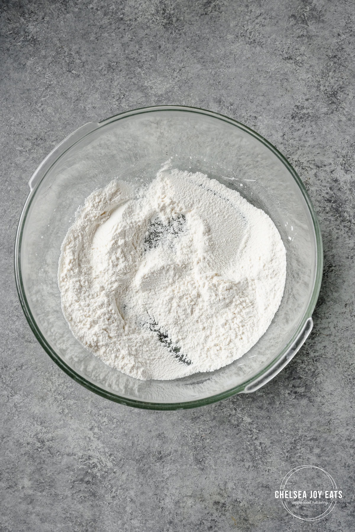 Gluten free flour and baking soda mixed in a glass bowl.