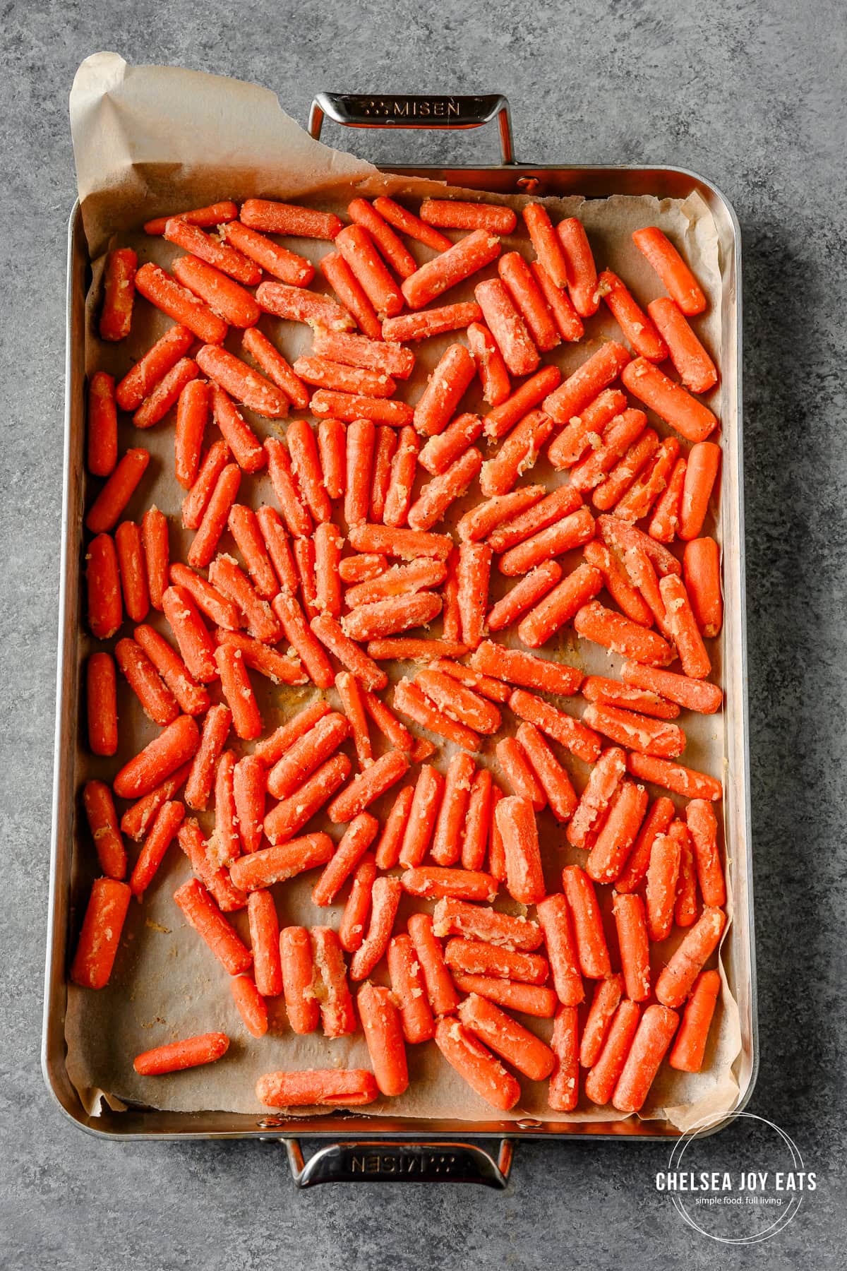 Unroasted carrots tossed in a honey butter glaze spread out on a sheet pan.