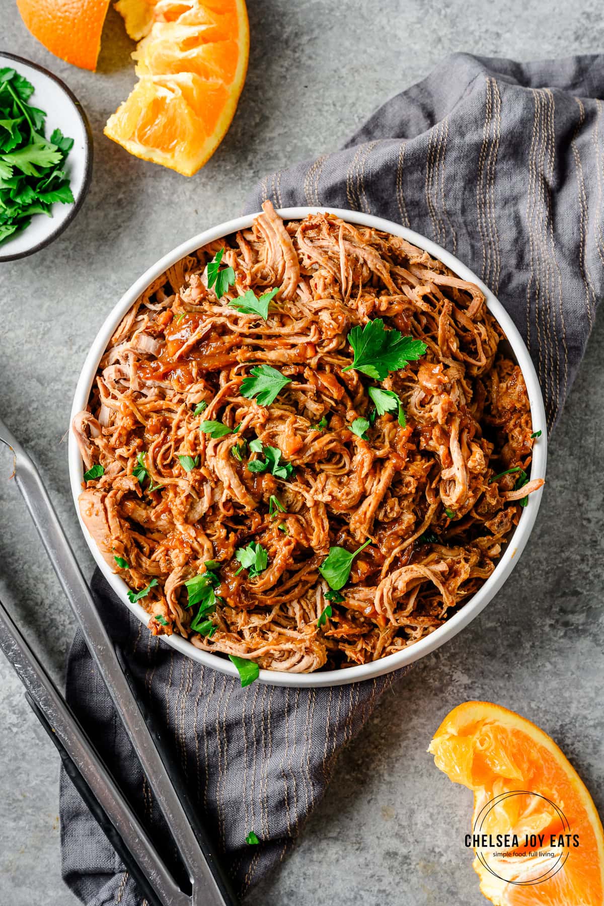 Miso orange shredded pork tenderloin in a serving bowl garnished with parsley.