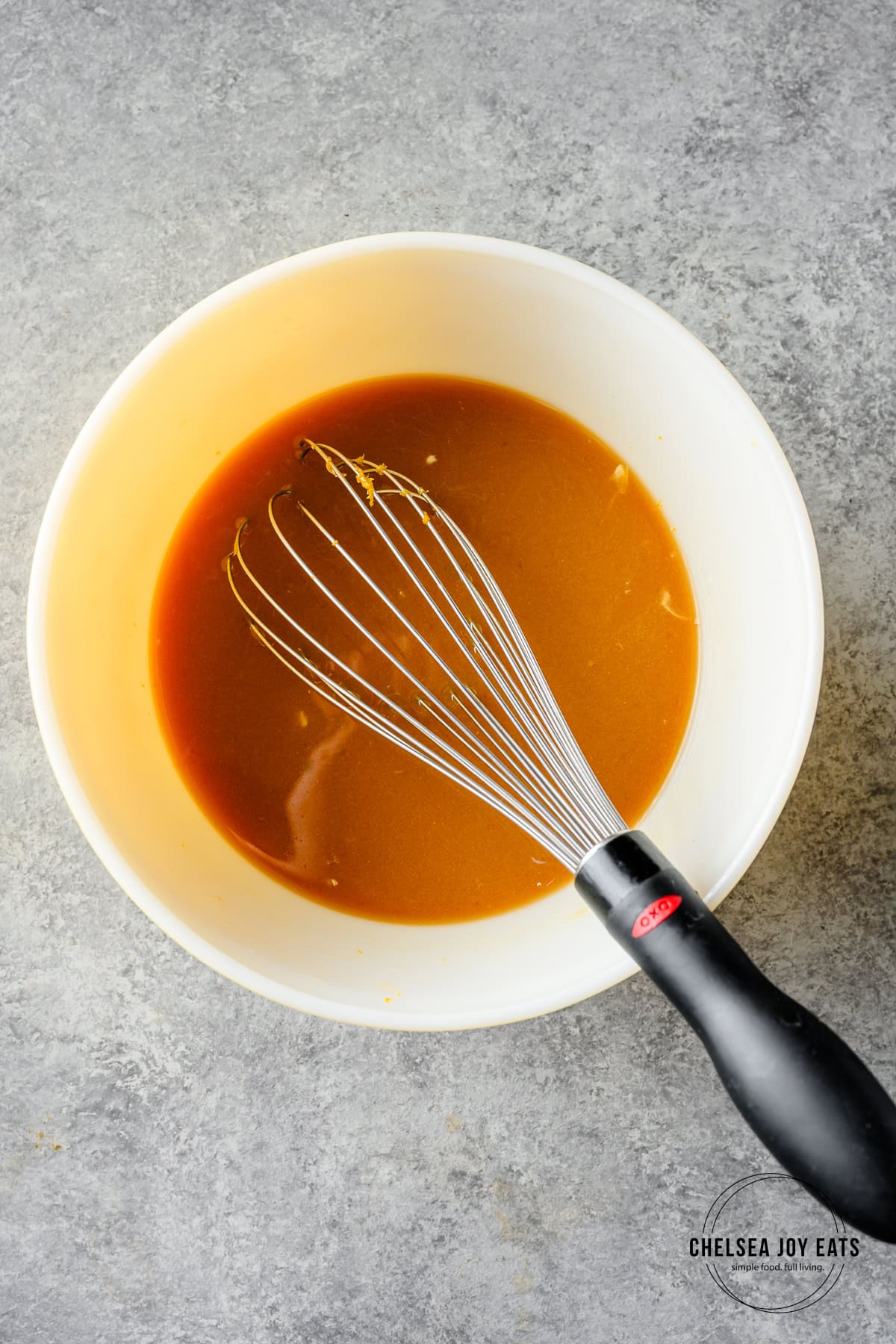 Miso orange braising sauce in a mixing bowl with a whisk.