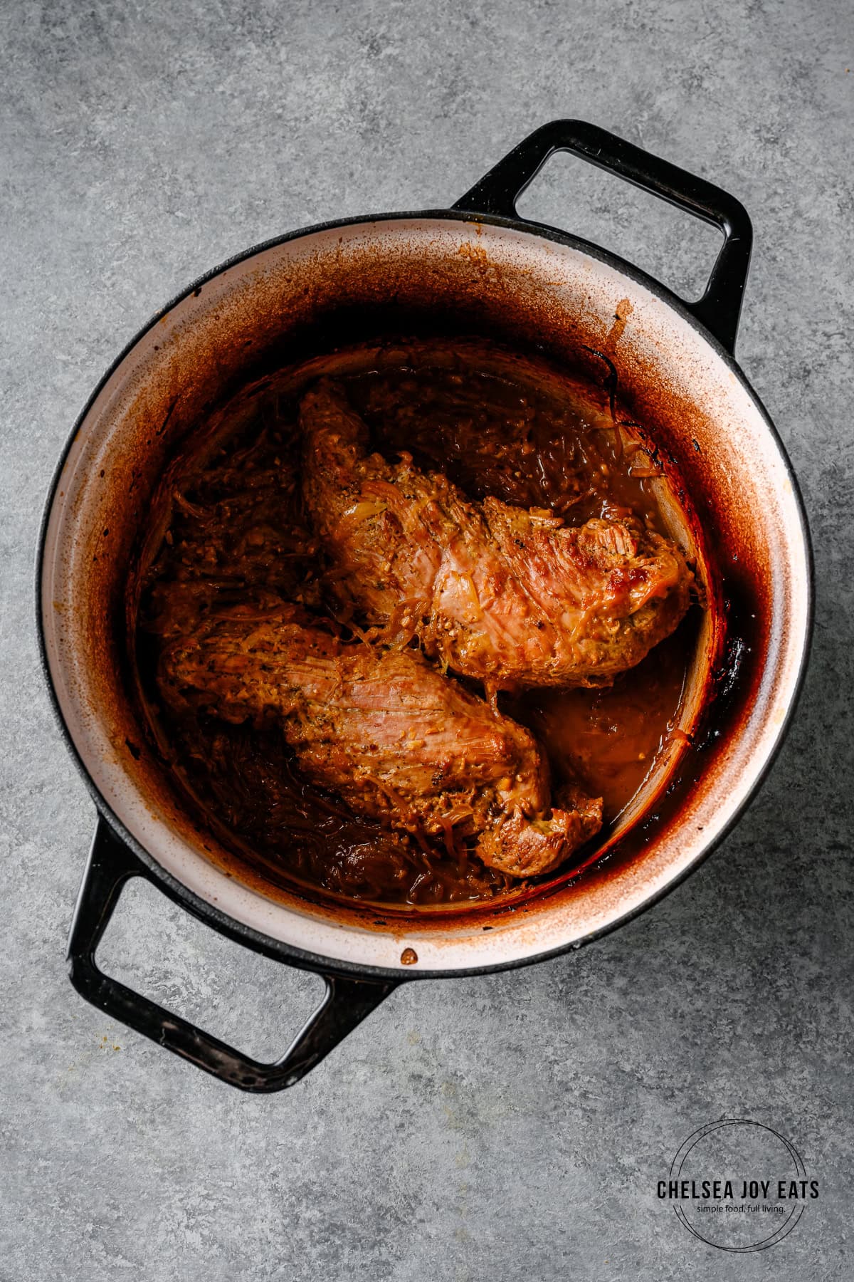 Cooked miso orange pork tenderloin in a Dutch oven before being shredded.