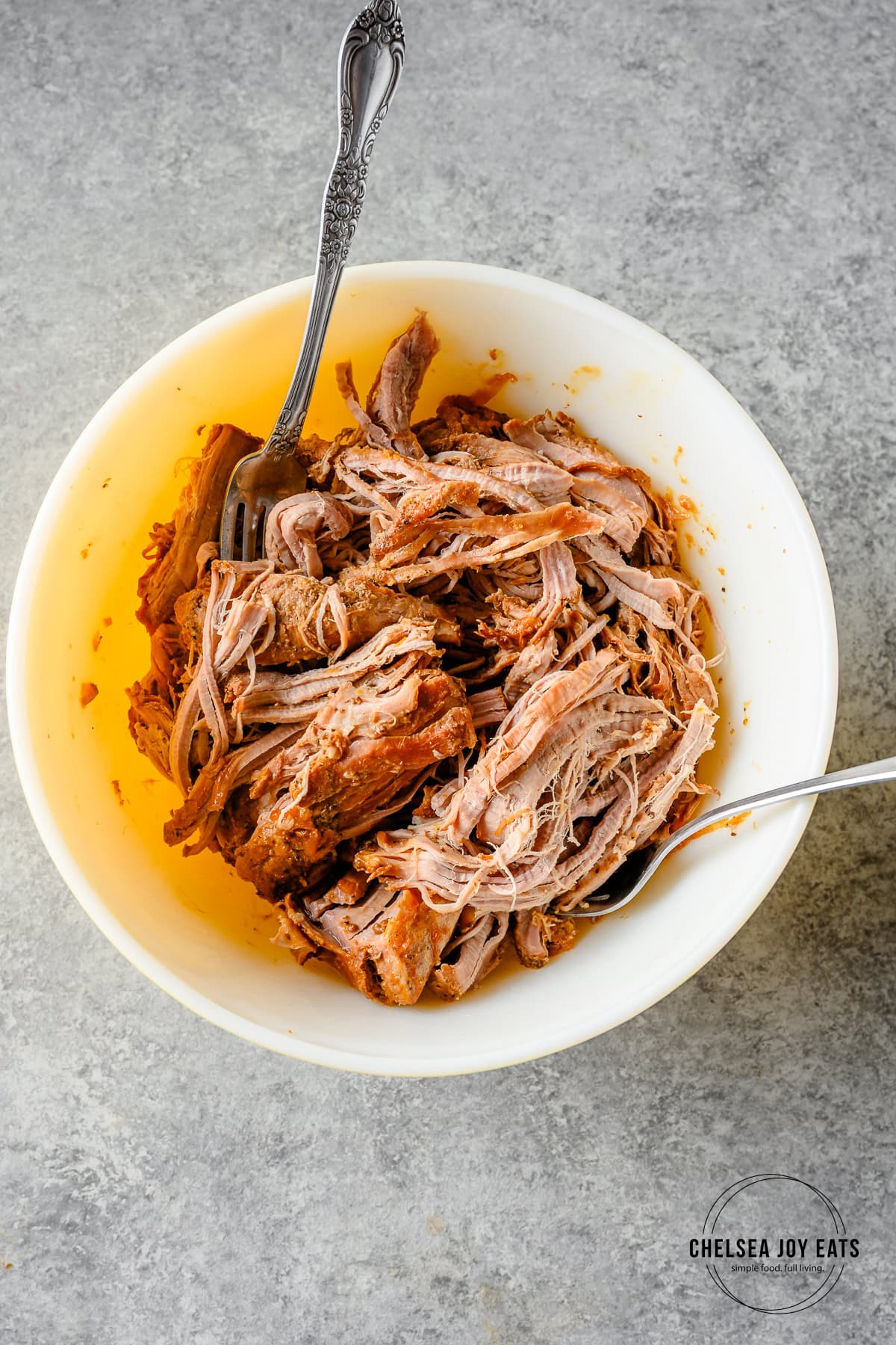 Shredded pork tenderloin in a bowl with two forks.