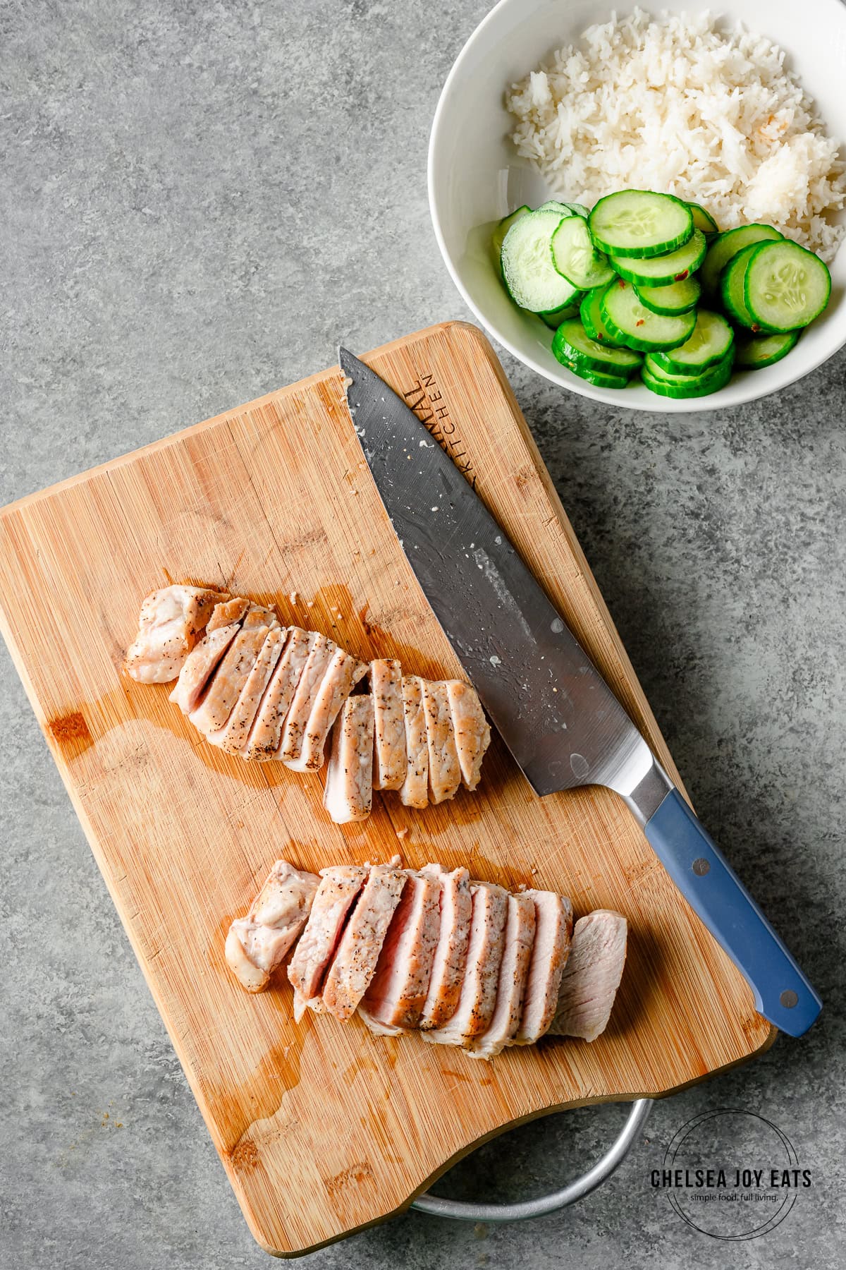 Cooked pork chops sliced on a cutting board with the knife alongside.
