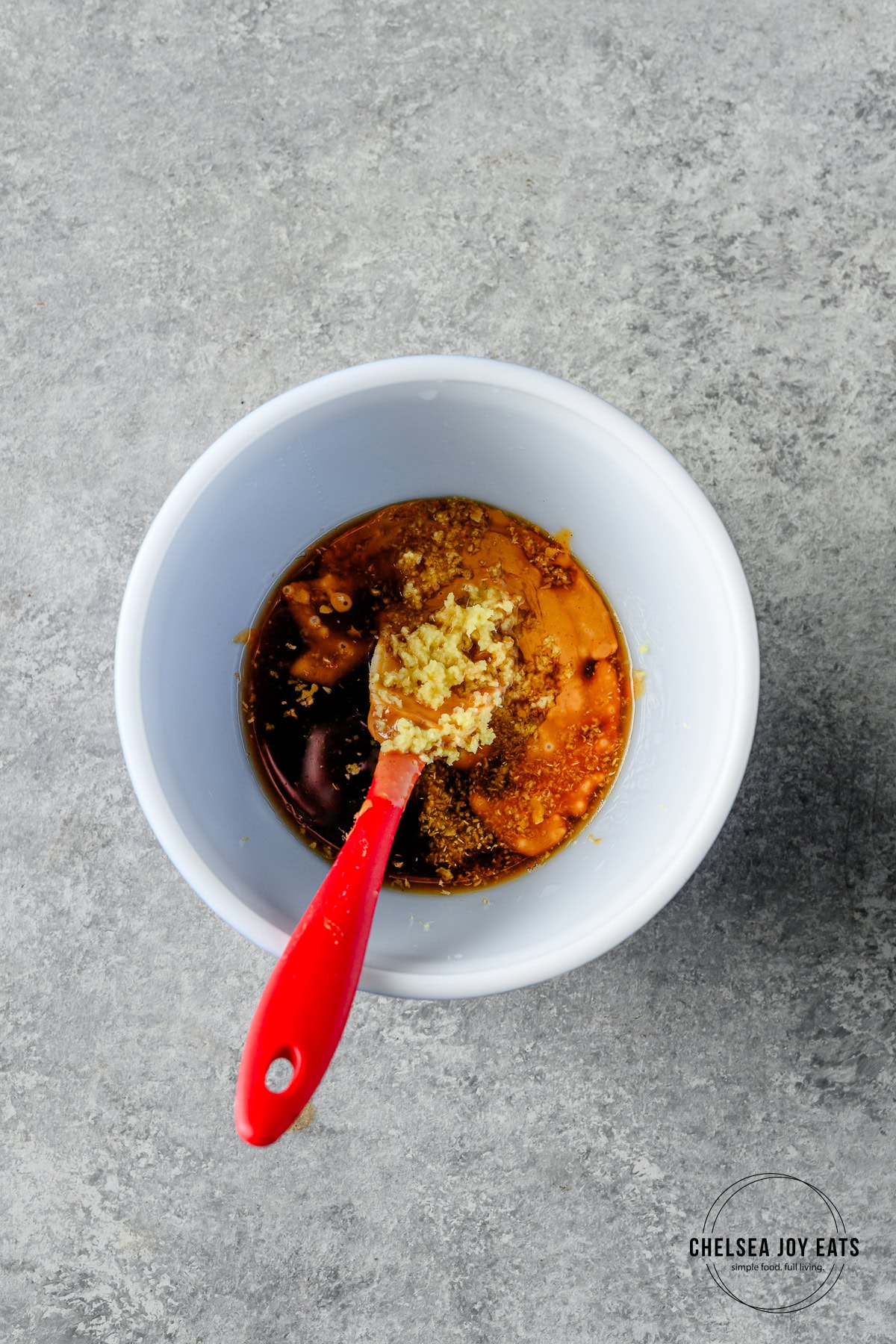 Ingredients for Thai peanut sauce in a small bowl with a spatula to stir.