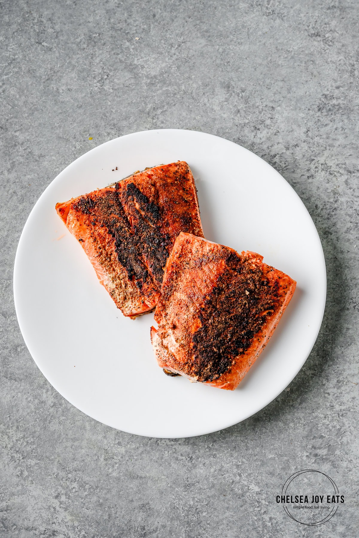 Blackened salmon fillets on a white ceramic plate.