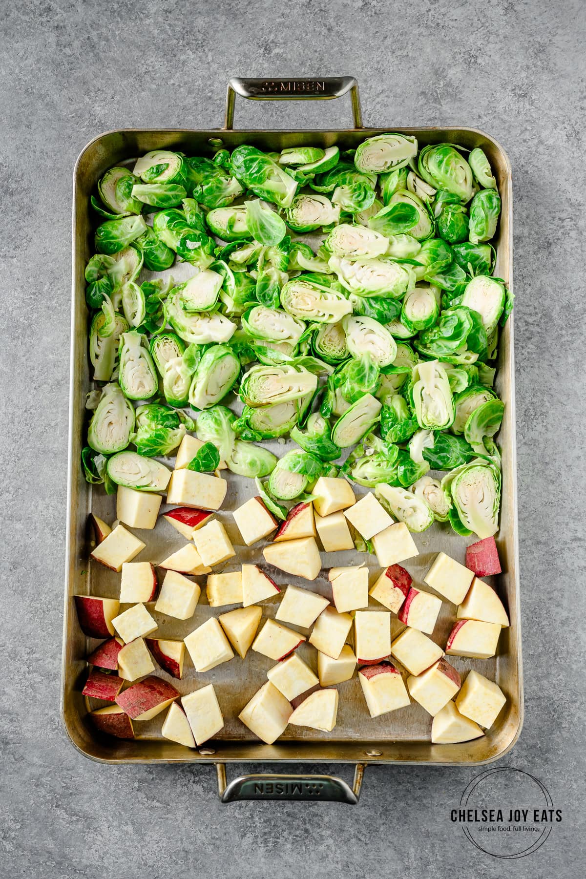 Cubed sweet potatoes and sliced brussels sprouts spread out on a sheet pan.