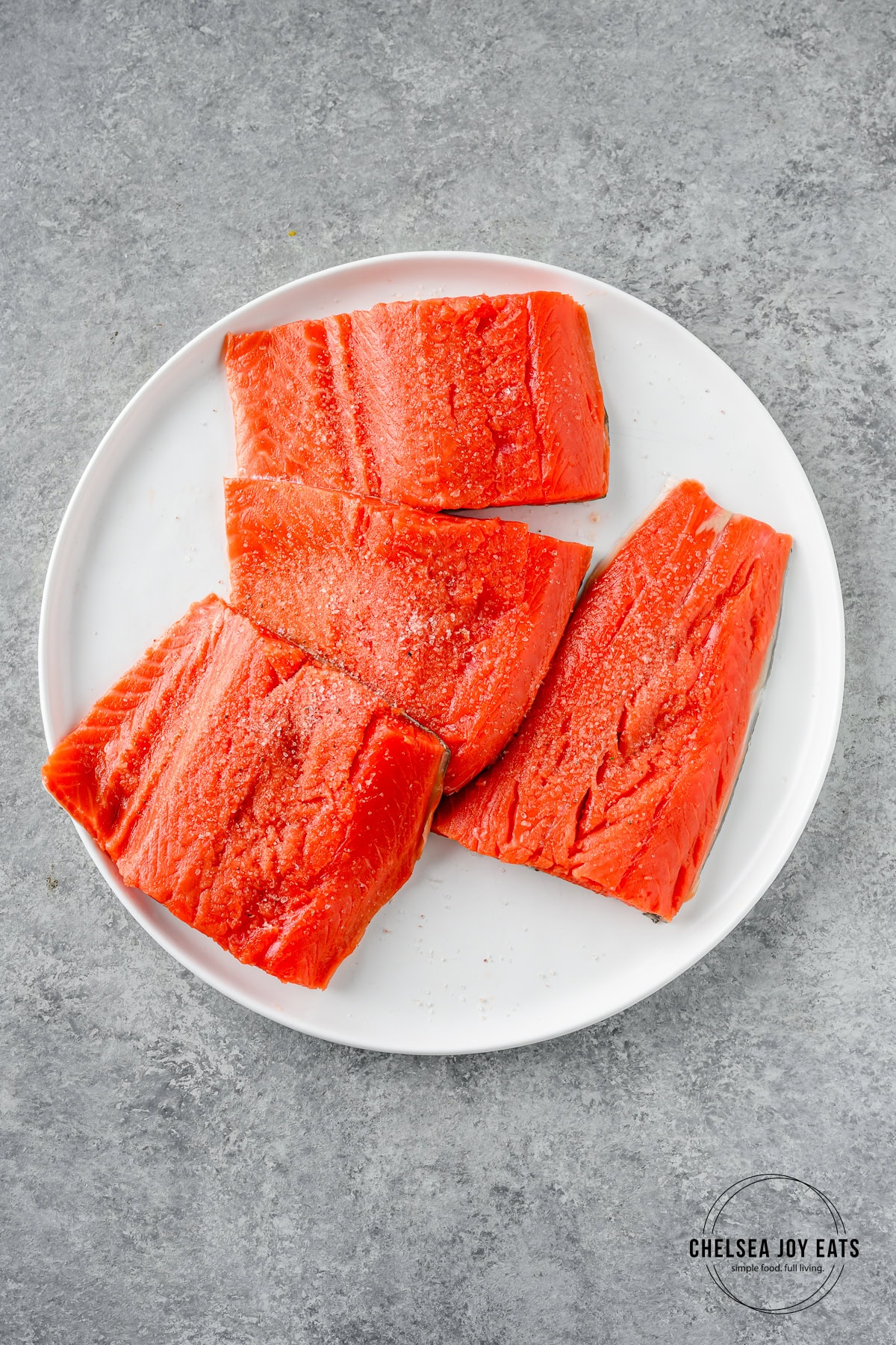 Salt-seasoned raw salmon fillets on a plate.