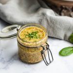 Small glass jar filled with mustard chive vinaigrette.