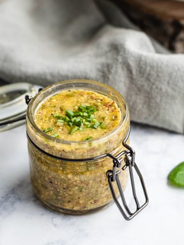 Small glass jar filled with mustard chive vinaigrette.