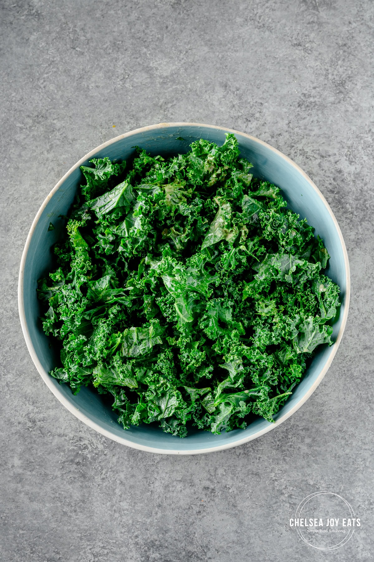 Chopped kale tossed with a little dressing in a large serving bowl.
