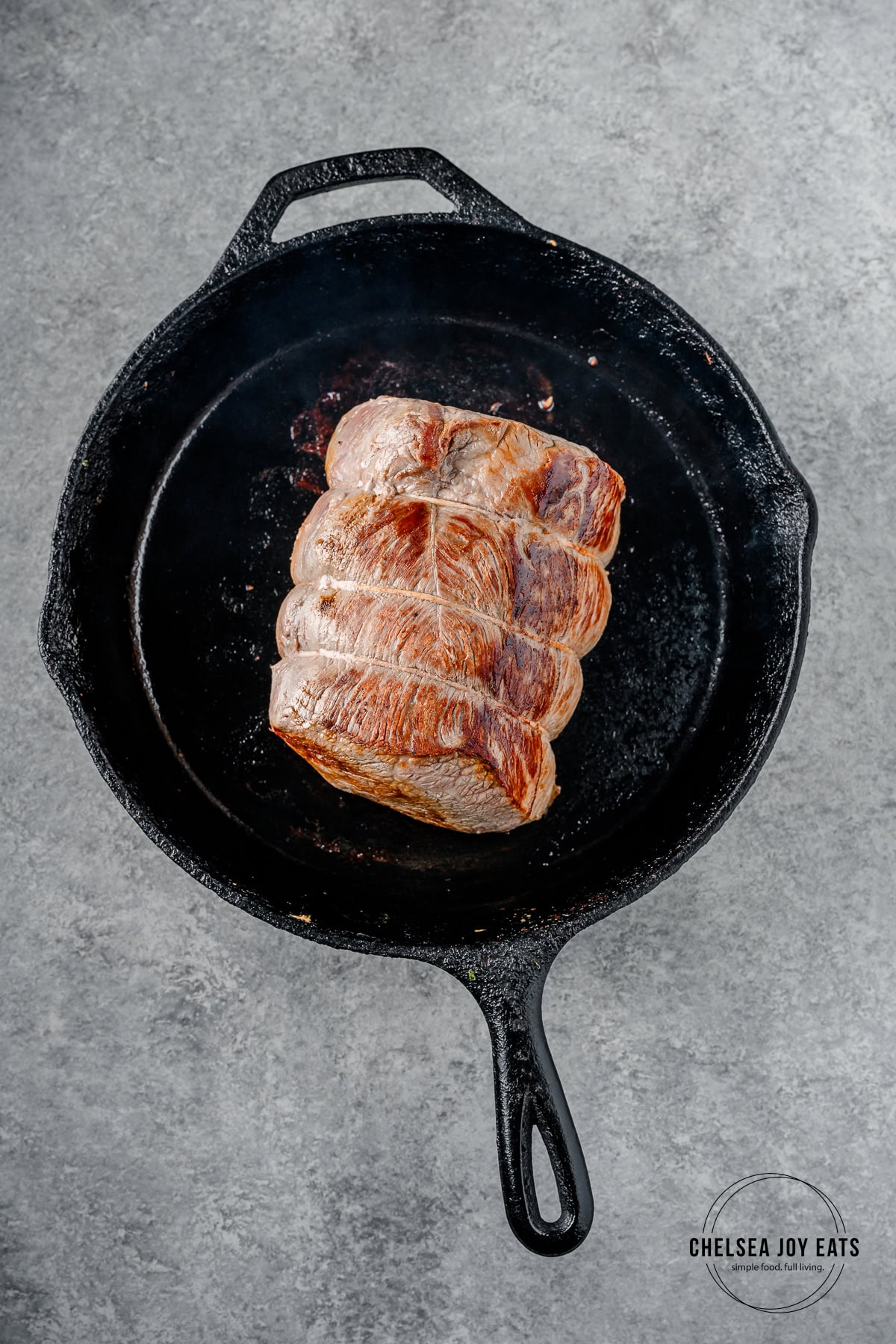 Beef roast searing in a cast iron skillet.