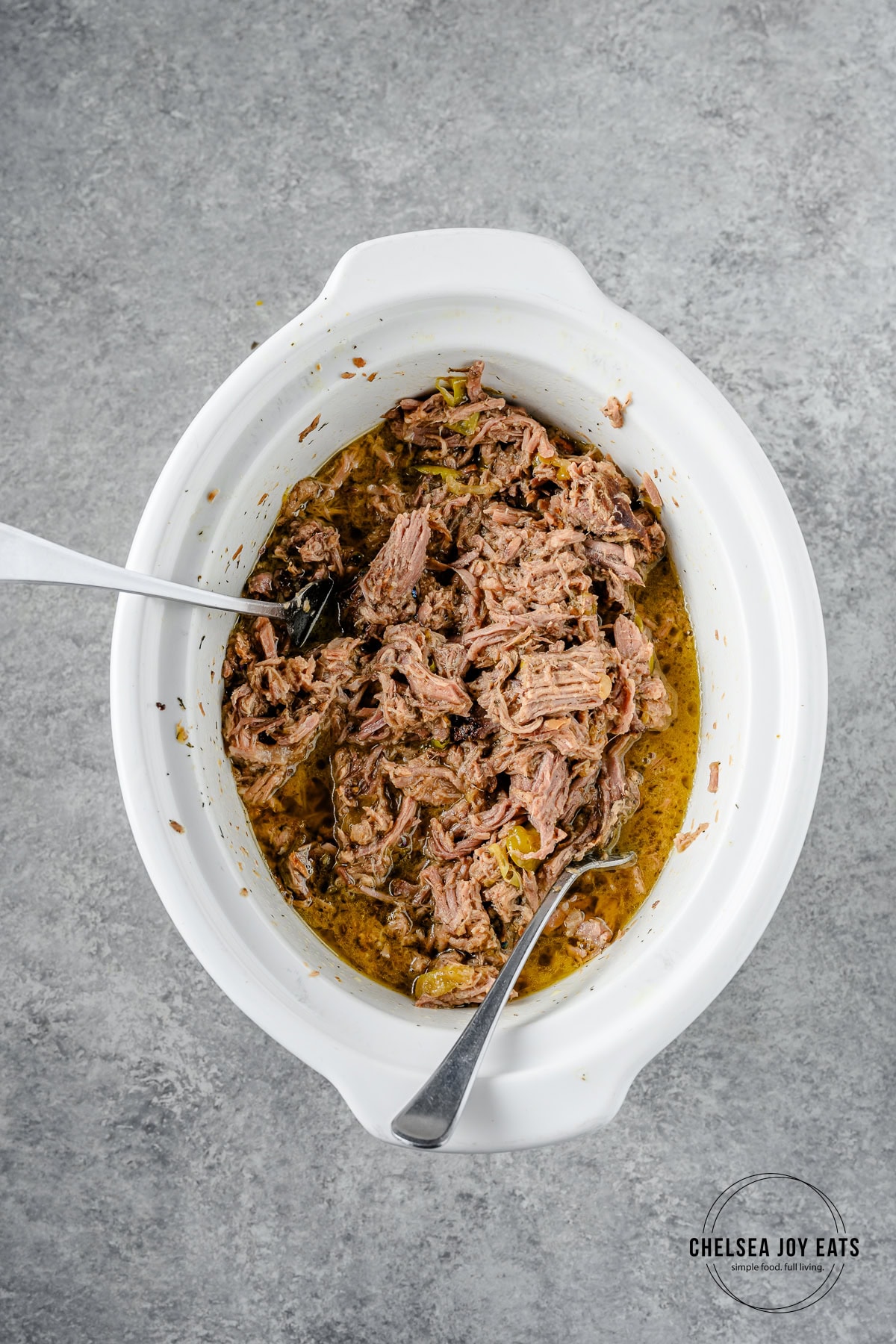 Shredded gluten free mississippi pot roast in a crockpot, with two forks for shredding.