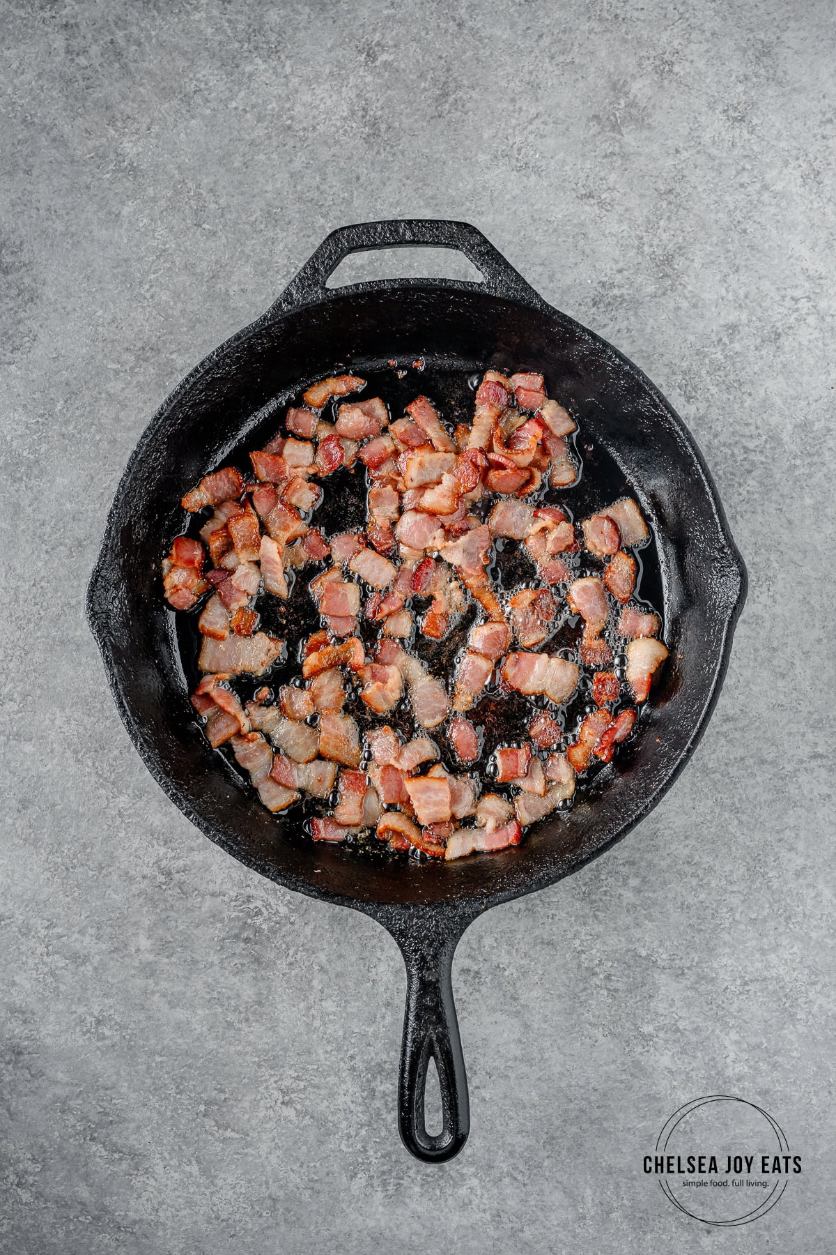Chopped bacon frying in a cast iron skillet.