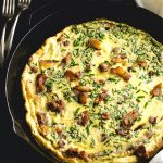 Bacon, Chive, and Plantain frittata in a cast iron skillet with forks alongside.