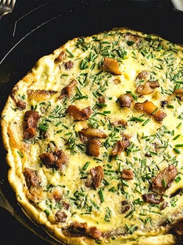 Bacon, Chive, and Plantain frittata in a cast iron skillet with forks alongside.