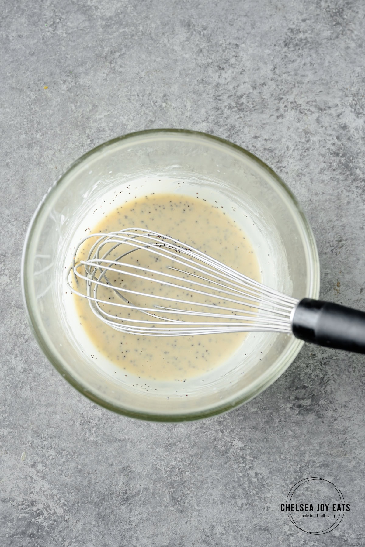 Lemon tahini poppyseed dressing whisked with a whisk in a medium glass bowl.