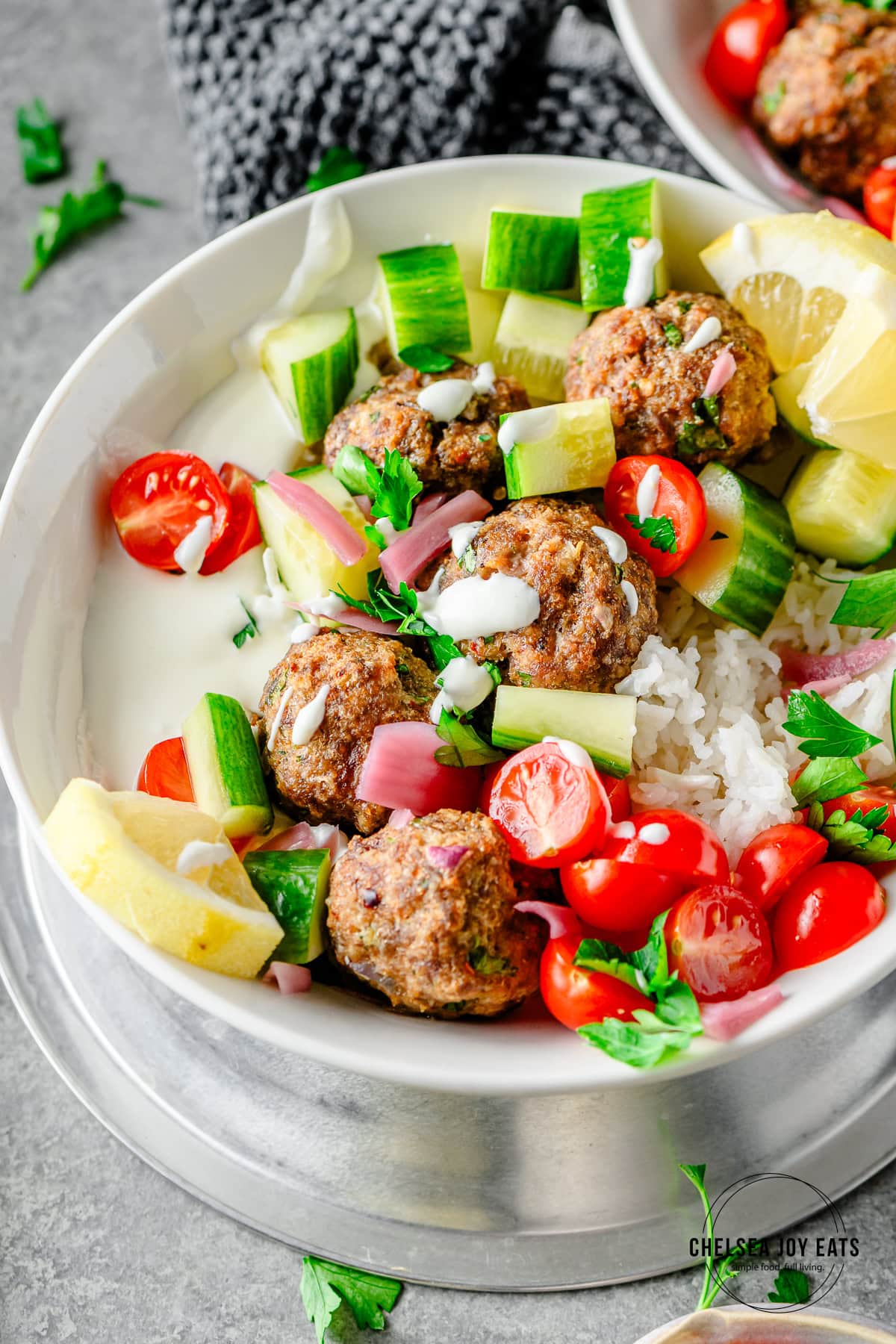 Dinner bowl with gluten free beef and lamb meatballs, rice, cucumber, tomato, and whipped feta sauce.