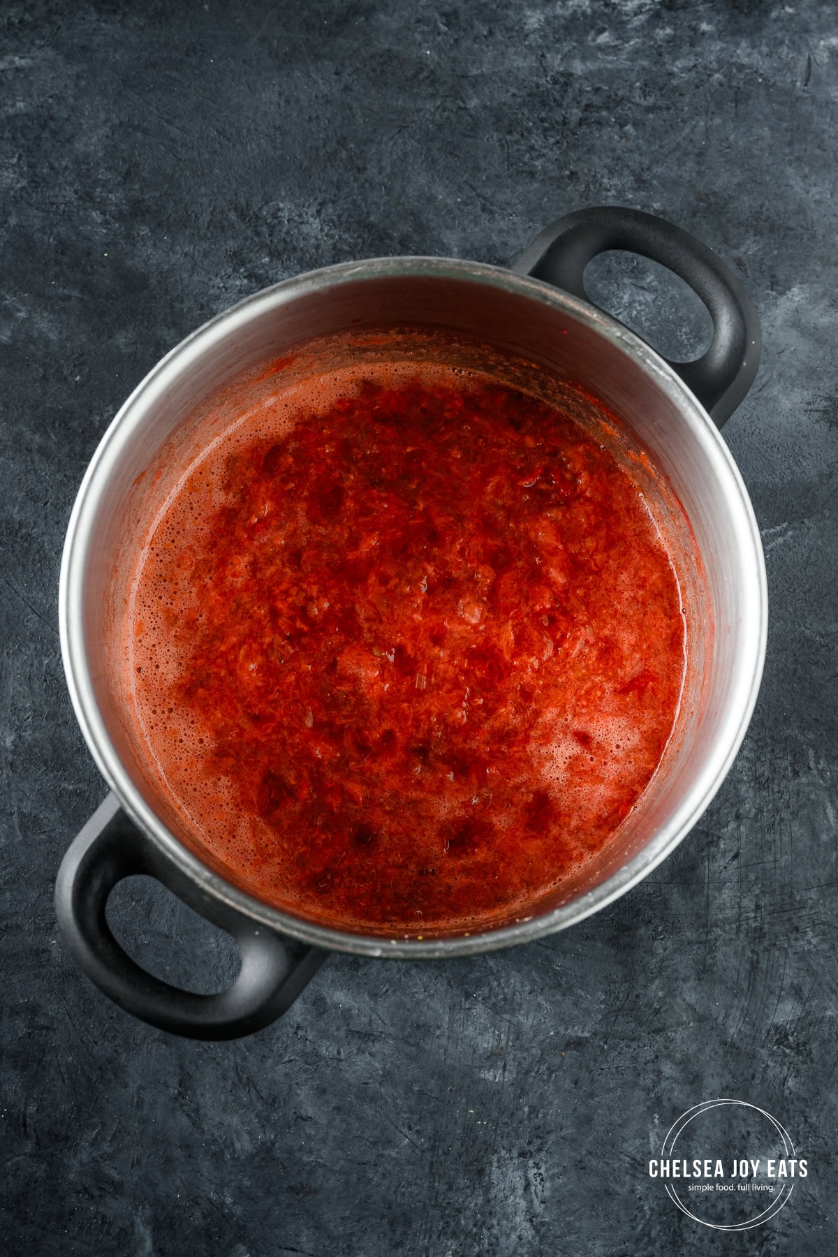 Strawberries and rhubarb cooked down to a mash in a deep pot.