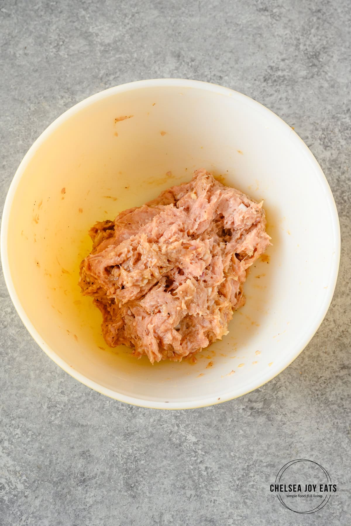 Ground chicken mixed with spices in a ceramic bowl.