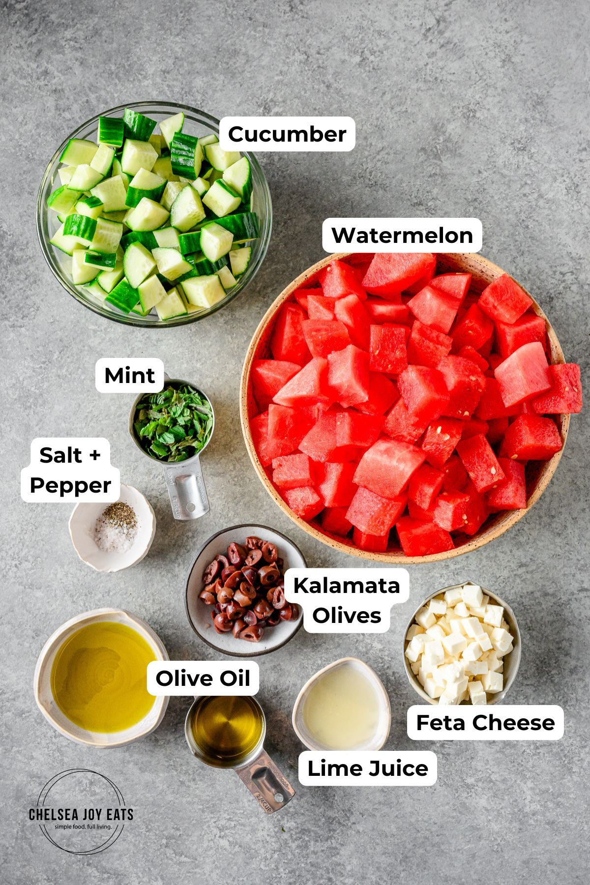 Ingredients for a Greek-inspired Cucumber and Watermelon Salad in individual bowls with text labels for each ingredient.
