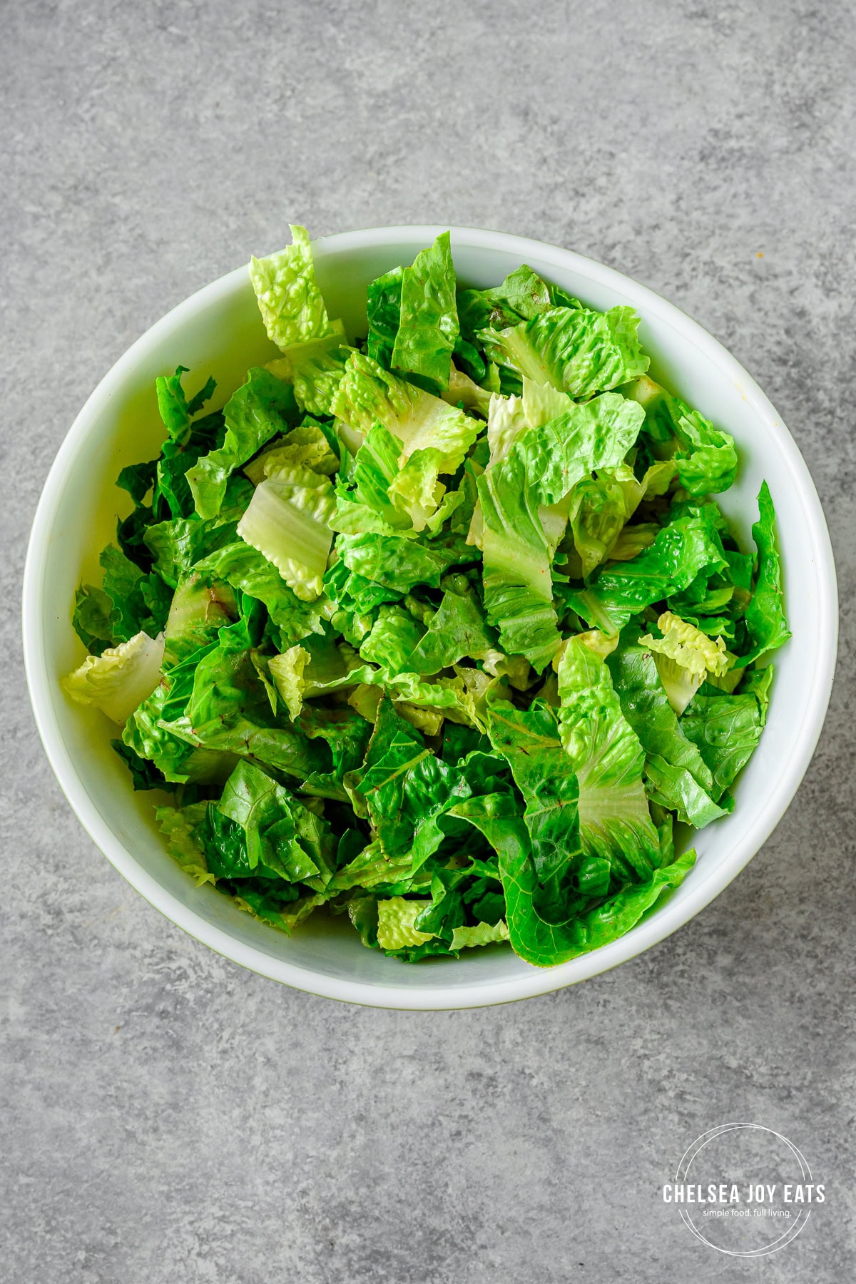 Chopped romaine lettuce in a large bowl tossed with a bit of bacon vinaigrette.