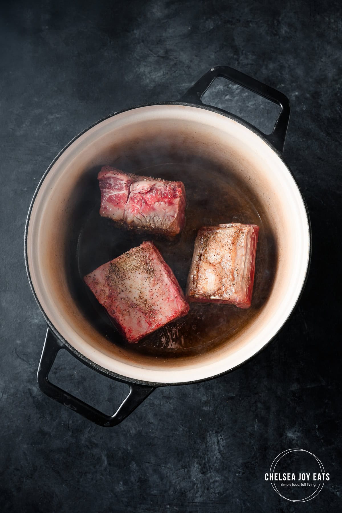 Beef short ribs searing in a Dutch oven.
