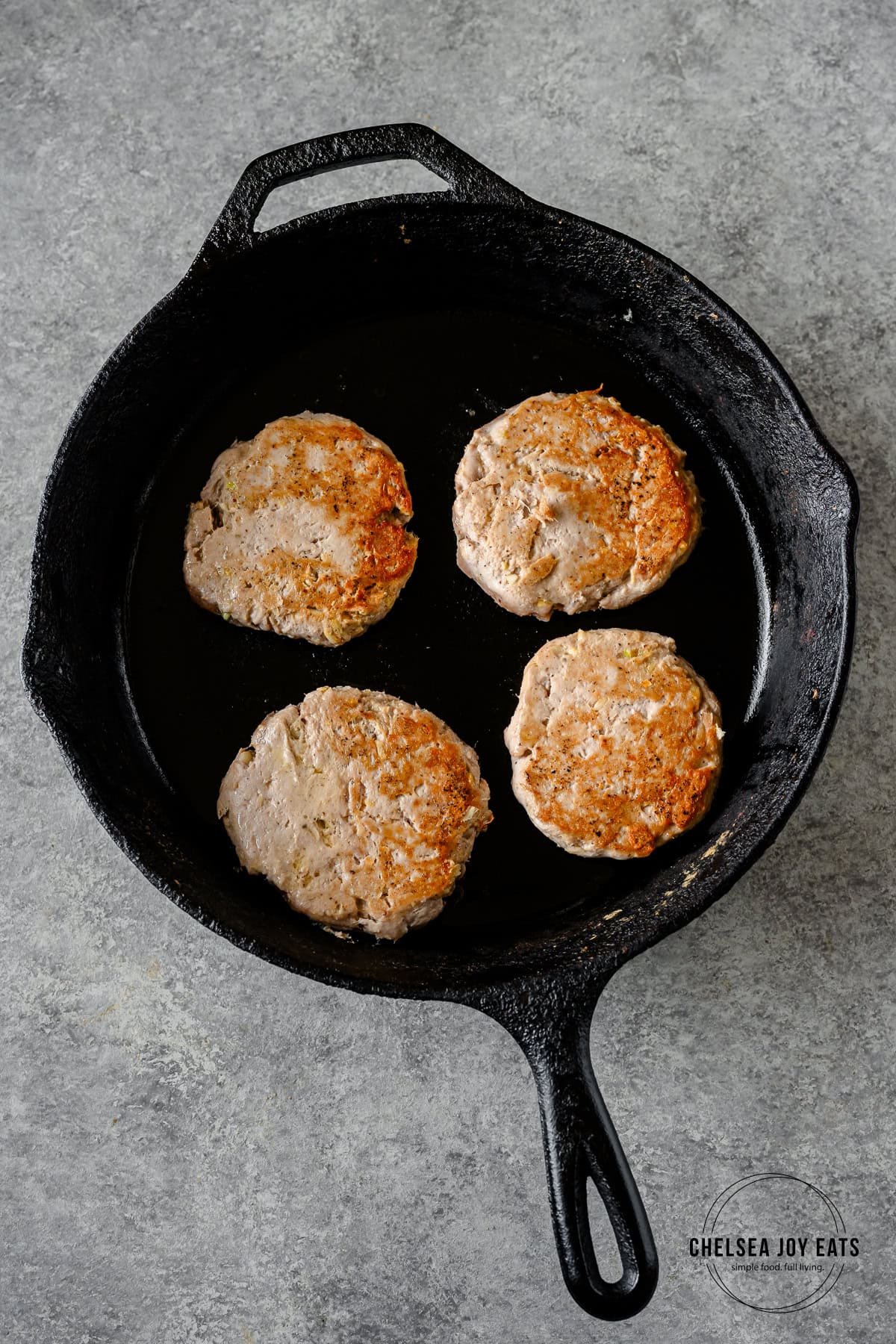 Tuna patties beign cooked in a cast iron skillet.