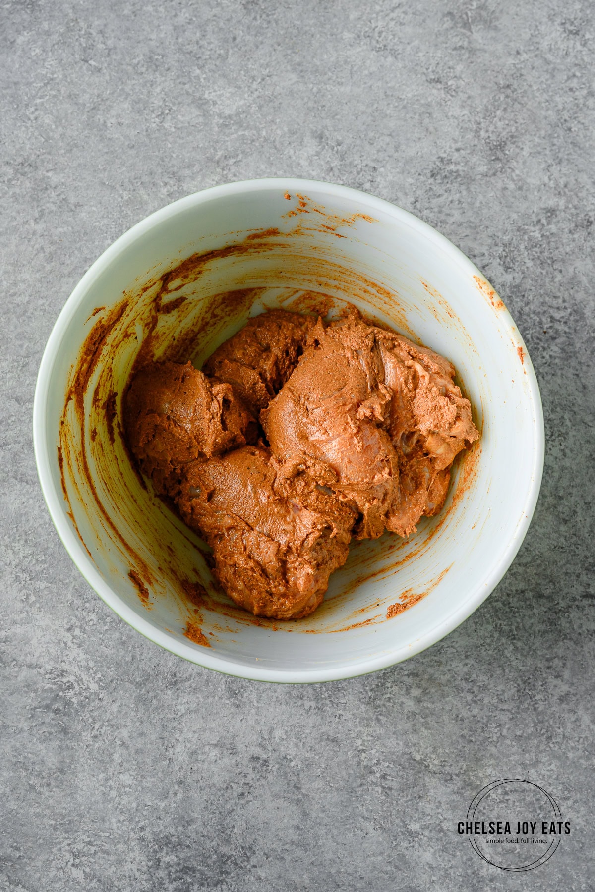 Chicken breast coated in a yogurt-based shawarma spice marinade in a large ceramic bowl.