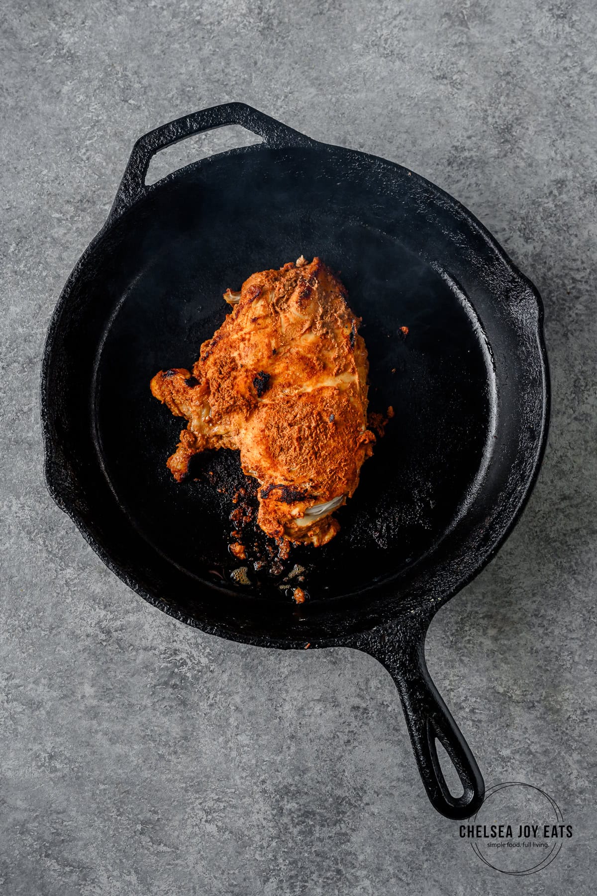 Marinated shawarma chicken breast cooking in a cast iron skillet.