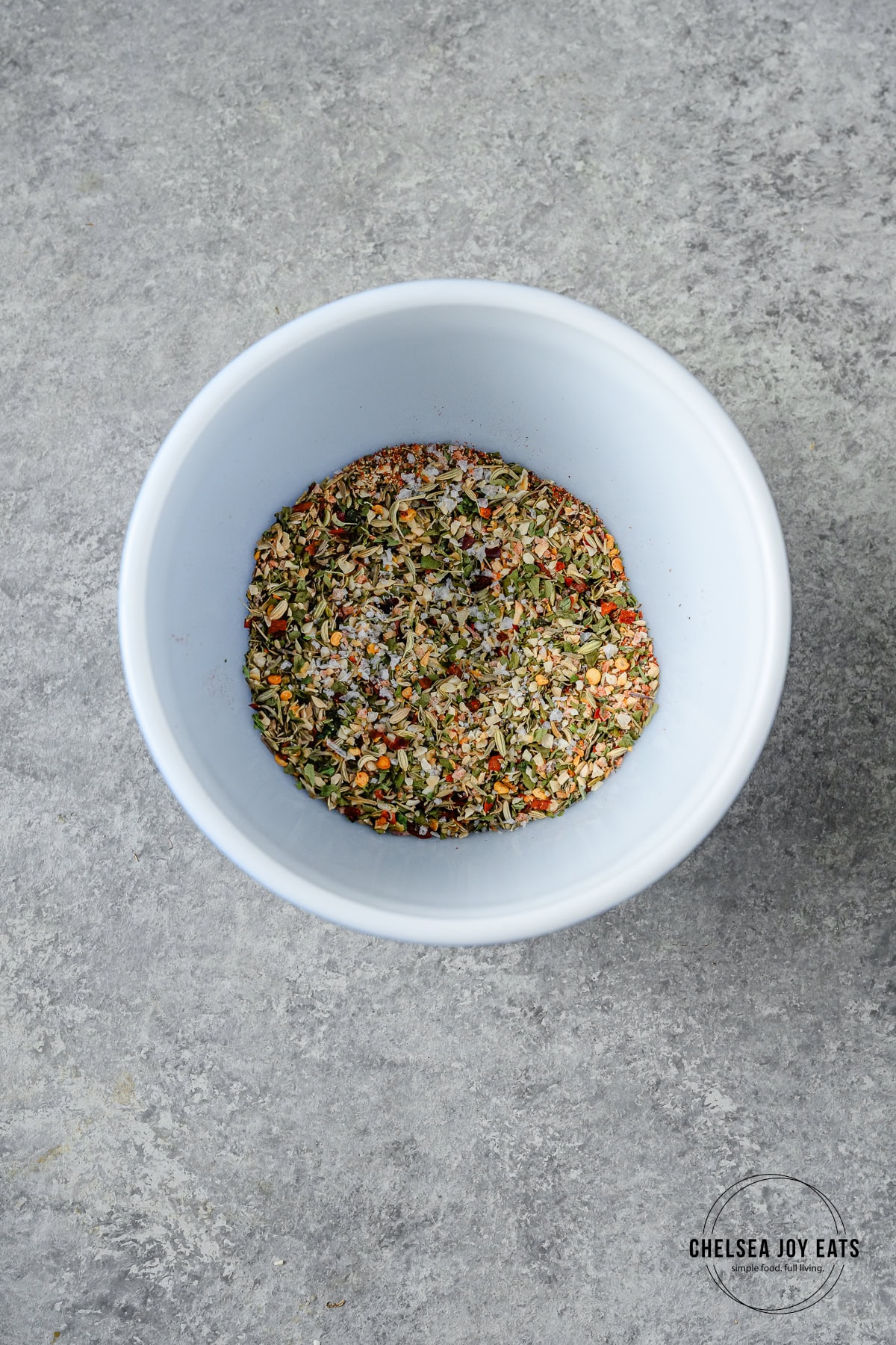 Blend of Italian seasoning in a small ceramic bowl on a white countertop.