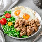 Italian Turkey Breakfast Sausage on a plate with an arugula salad and fried eggs.