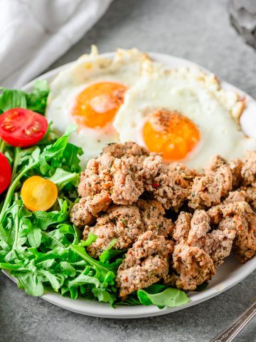 Italian Turkey Breakfast Sausage on a plate with an arugula salad and fried eggs.