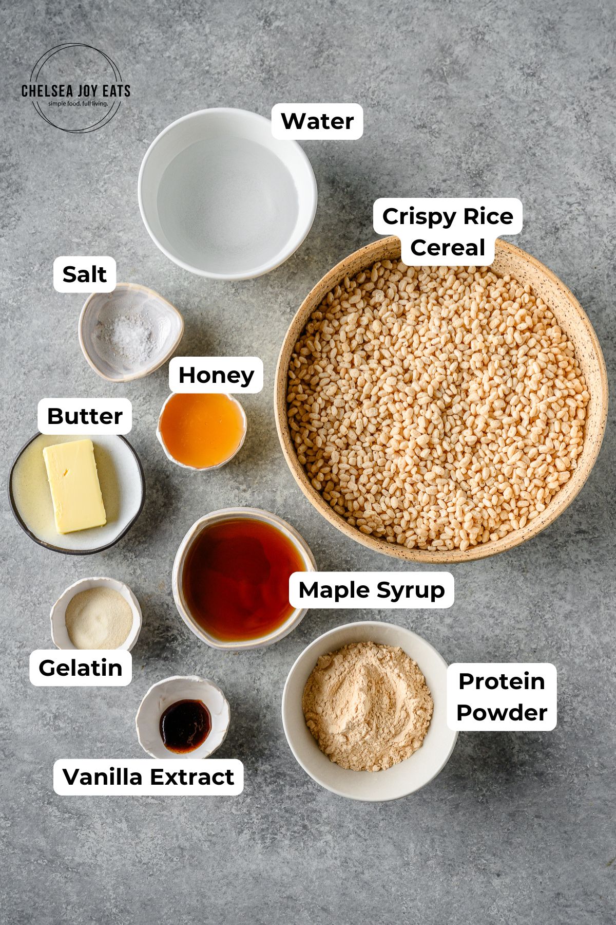 Ingredients for homemade protein rice krispies treats in individual bowls with text labels for each ingredient.