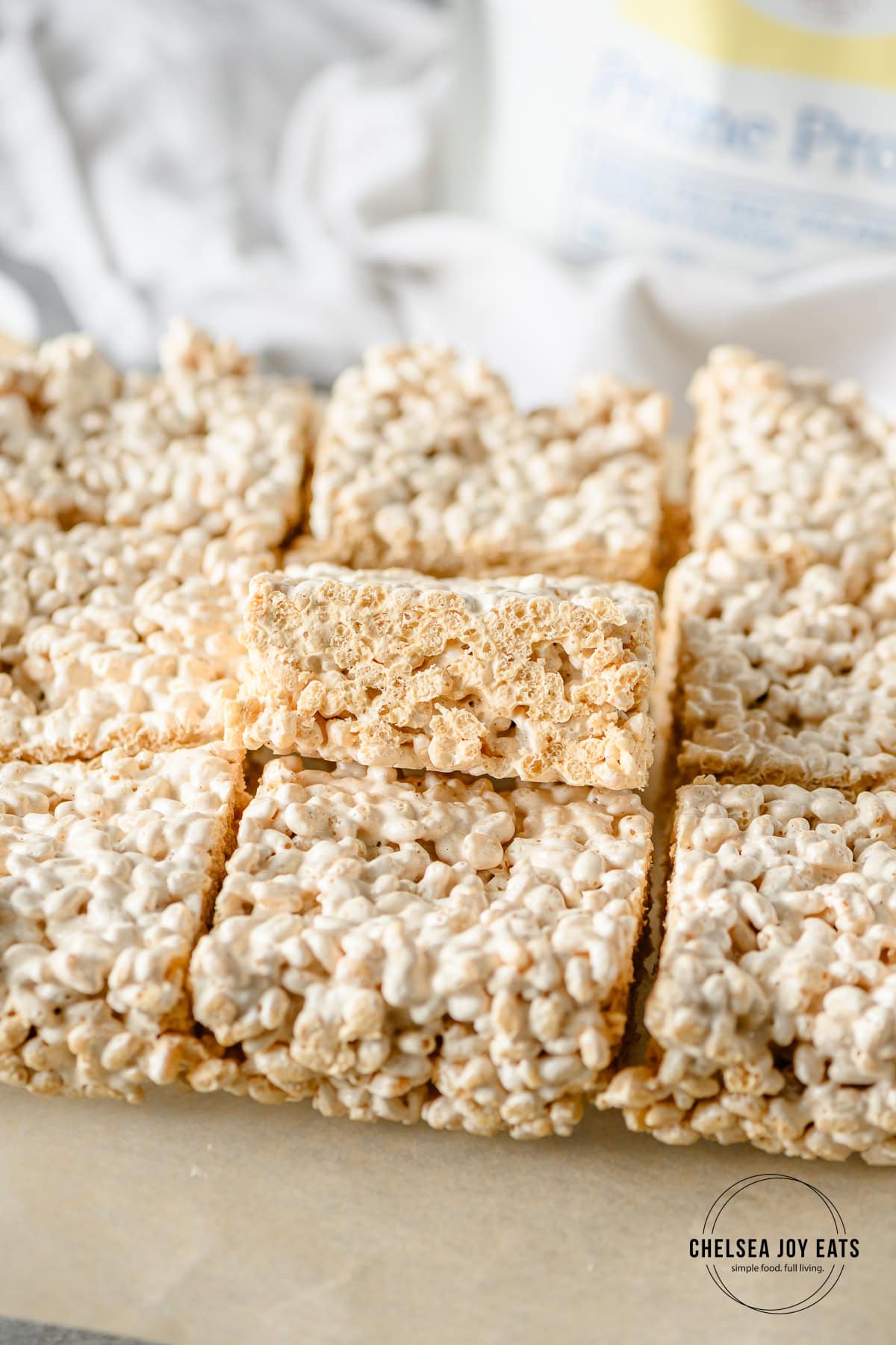 Rows of homemade protein rice krispies bars with one bar propped up to show the texture.