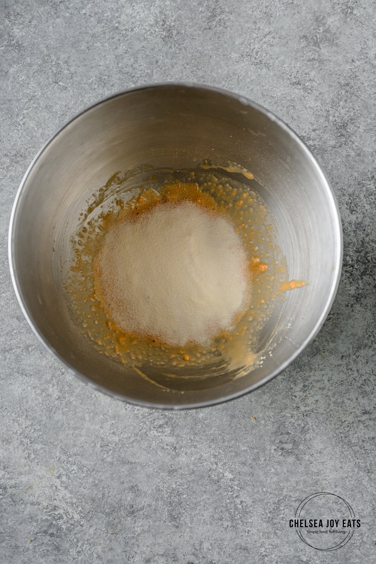 Gelatin sprinkled overtop a mixture of protein powder and water in the bowl of a stand mixer.