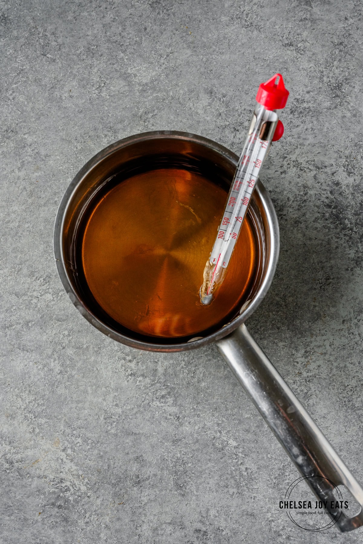 Honey and maple syrup mixture in a saucepan with a candy thermometer clipped to the side.