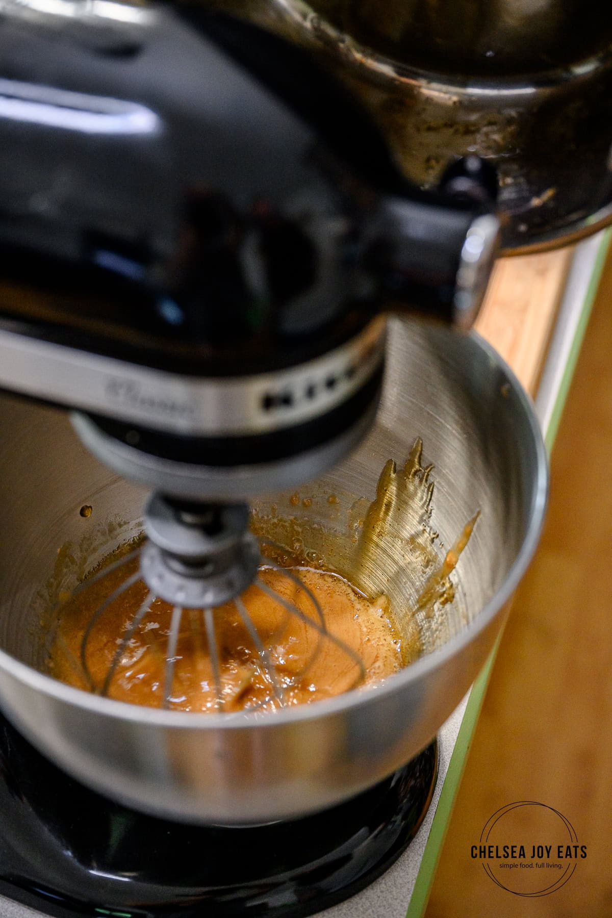 Hot syrup being poured into the bowl of a stand mixer with gelatin and water.