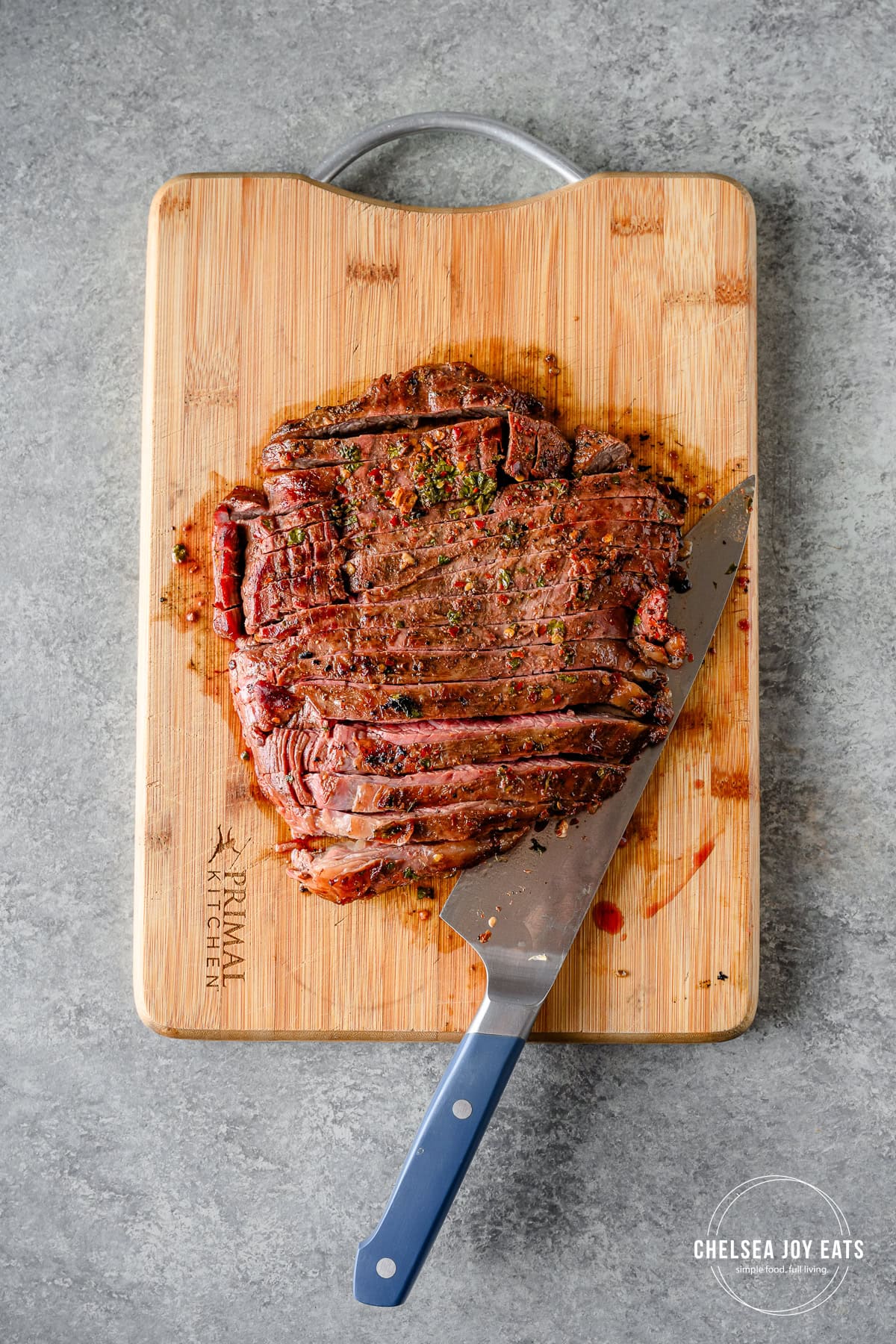 Grilled flank steak sliced on a cutting board against the grain after resting.