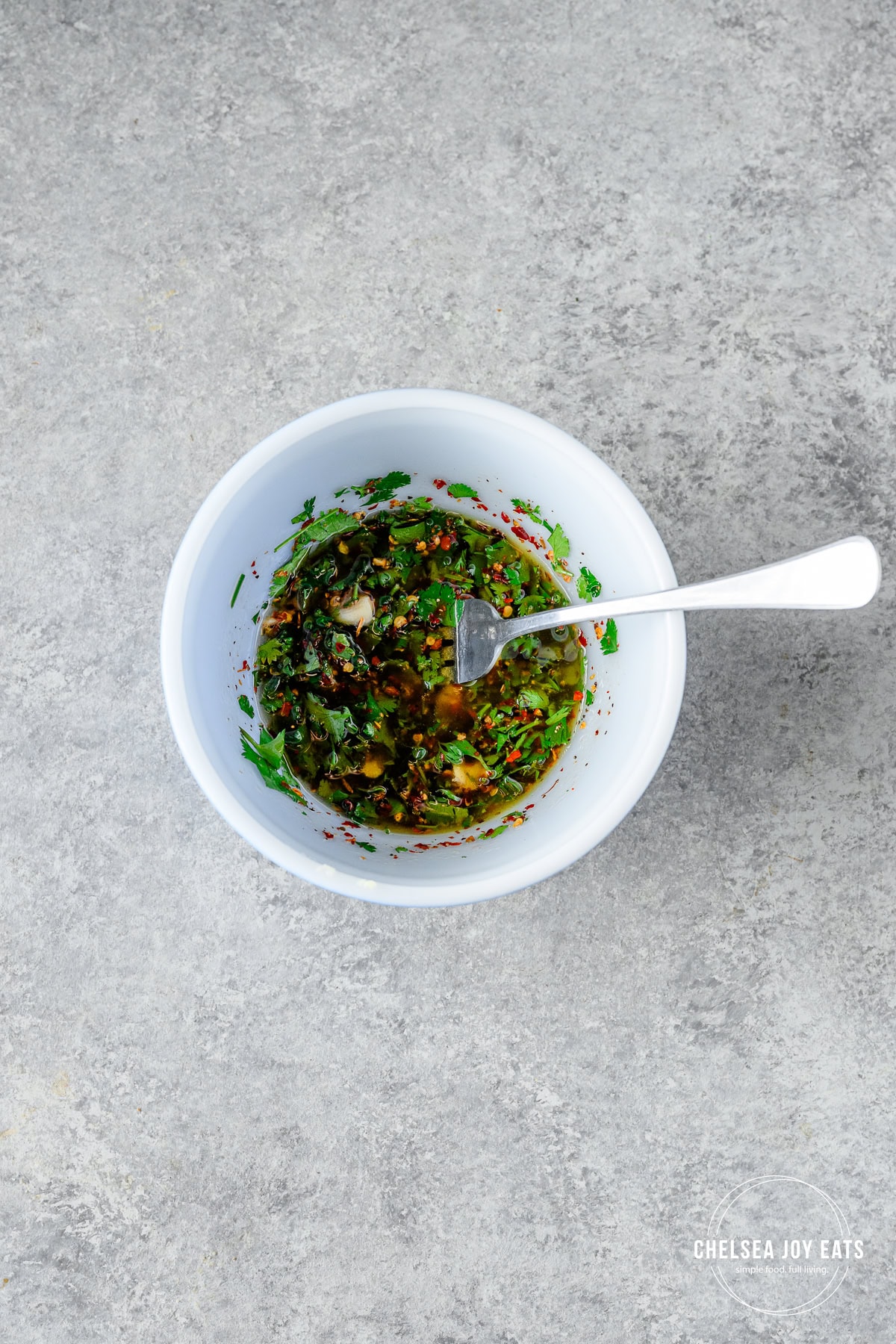 Simple parsley, red wine vinegar, garlic, and olive oil marinade combined in a small ceramic bowl.