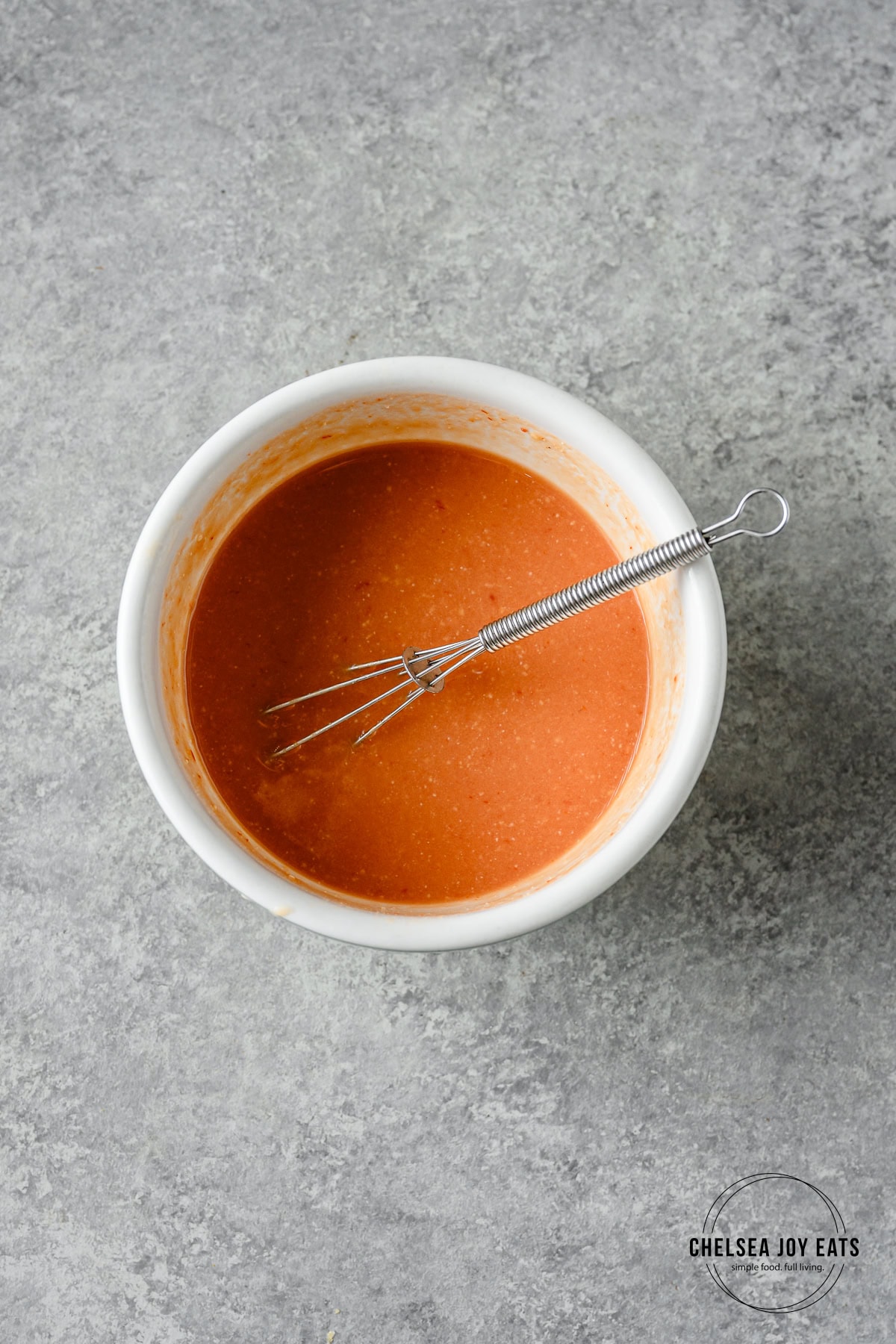 Ginger miso sauce blended together in a ceramic bowl with a small wire whisk.