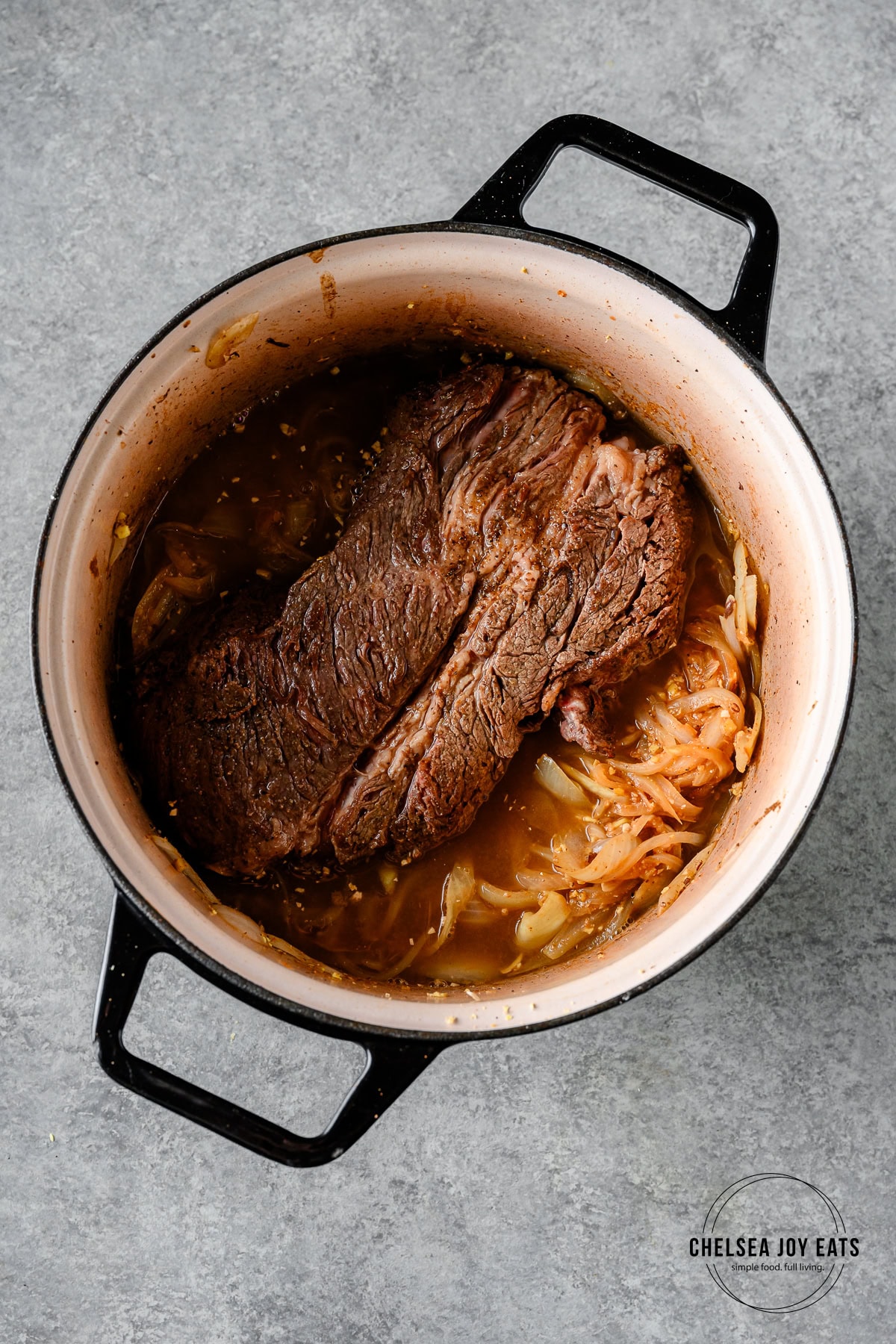 Chuck roast, onions, and miso ginger sauce in a Dutch oven ready to go in the oven.