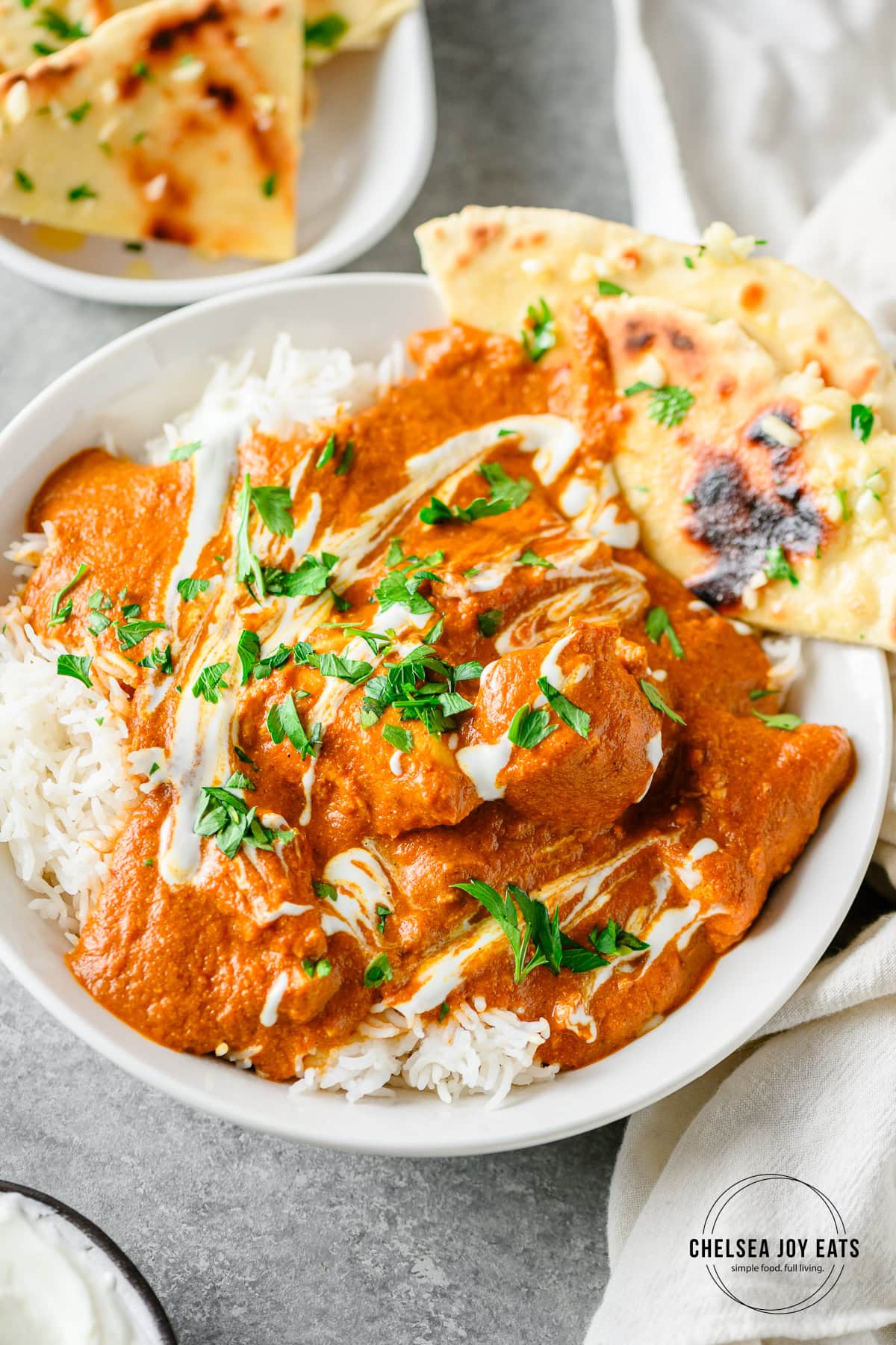 Homemade chicken breast tikka masala served over rice with gluten free flatbread in a white bowl.